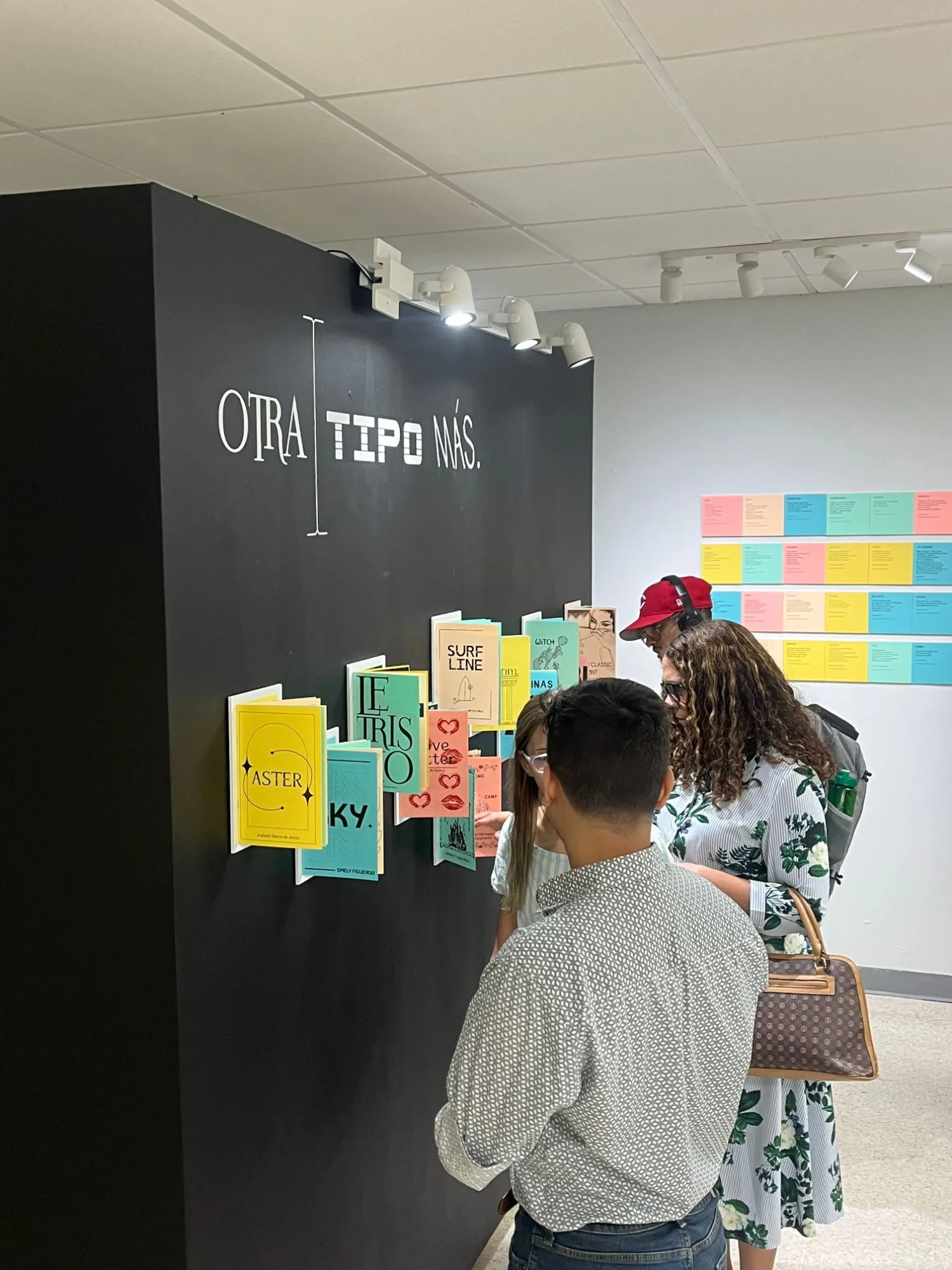 Visitors at the Otra Tipo Más exhibition, looking at a wall of type specimen booklets made by students